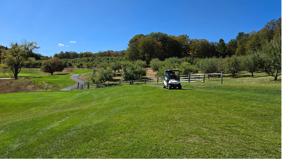 Banwell team in golf cart blue sky green grass